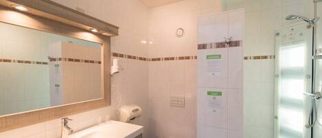 A modern bathroom with a sink, mirror, toilet, and shower.