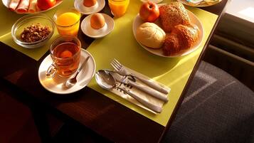 Un desayuno con diversas opciones de comida y un jarrón de flores sobre una mesa cerca de una ventana, con un cartel que dice 'Hotel'.