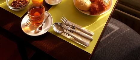A breakfast setup with various food items and a vase of flowers on a table by a window with a 'Hotel' sign.