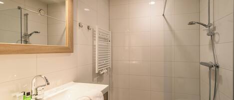 A modern bathroom with a white sink, mirror, and shower.