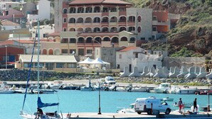 A coastal marina with boats, a white van, and a building with multiple balconies. - La Rosa Dei Venti (Buggerru)
