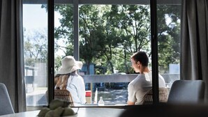 A room with a large window, a table with a bowl of snacks, and wicker furniture. - Adelaide Caravan Park (Hackney)