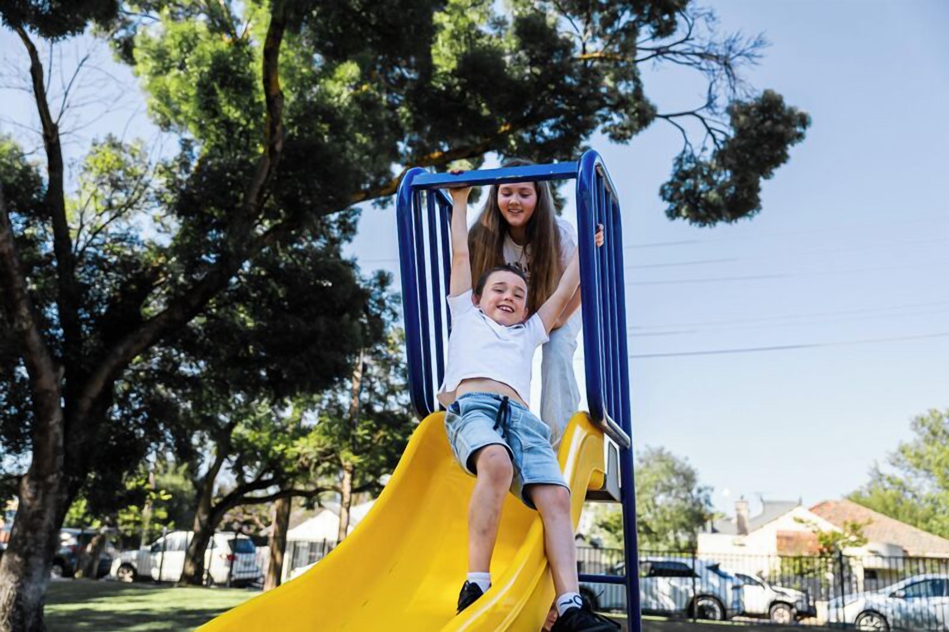 A playground with a yellow slide and blue monkey bars.