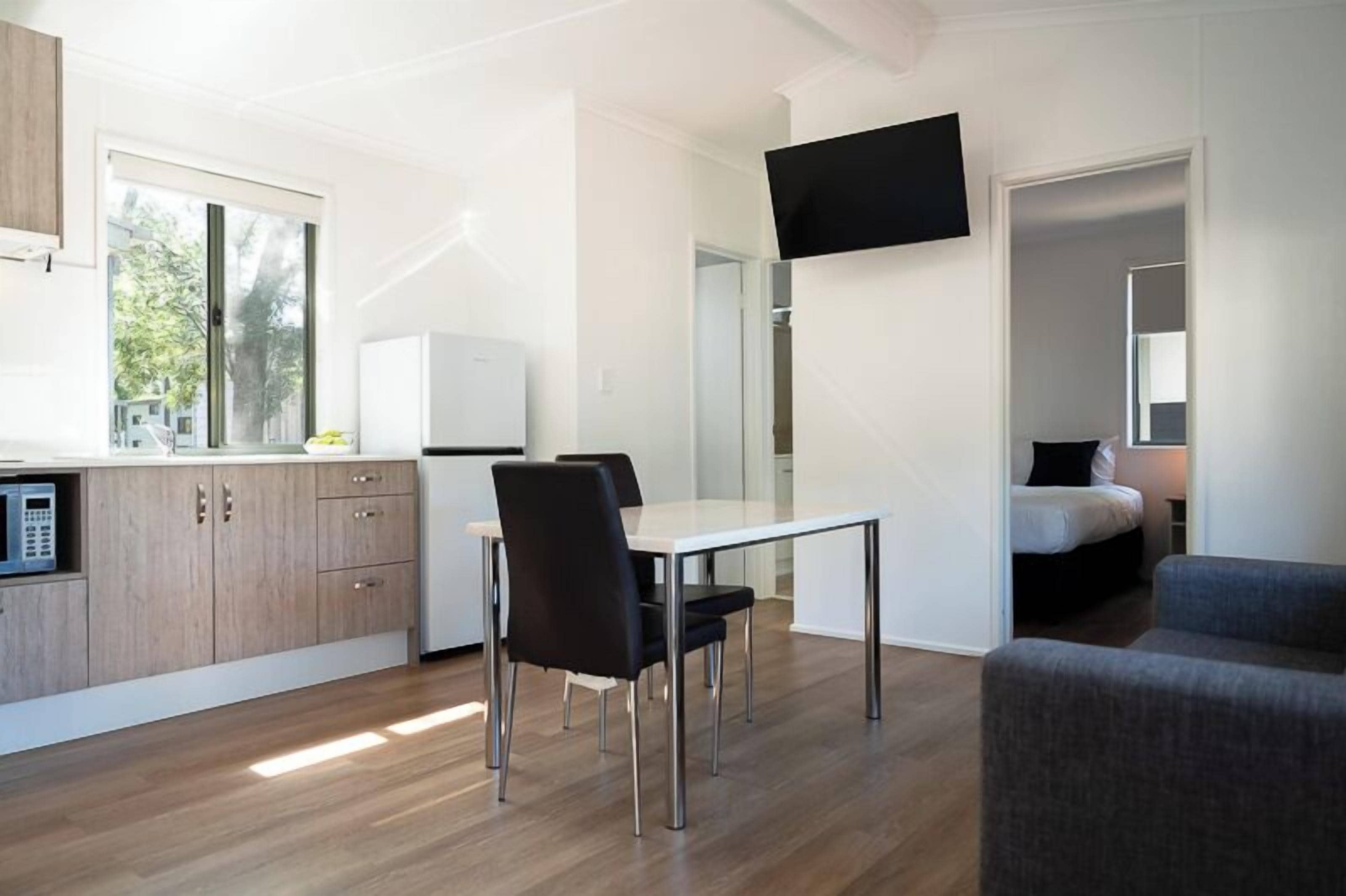 A modern, compact living space with a kitchenette, dining area, and a bed.