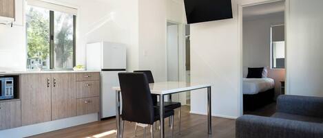 A modern, compact living space with a kitchenette, dining area, and a bed.
