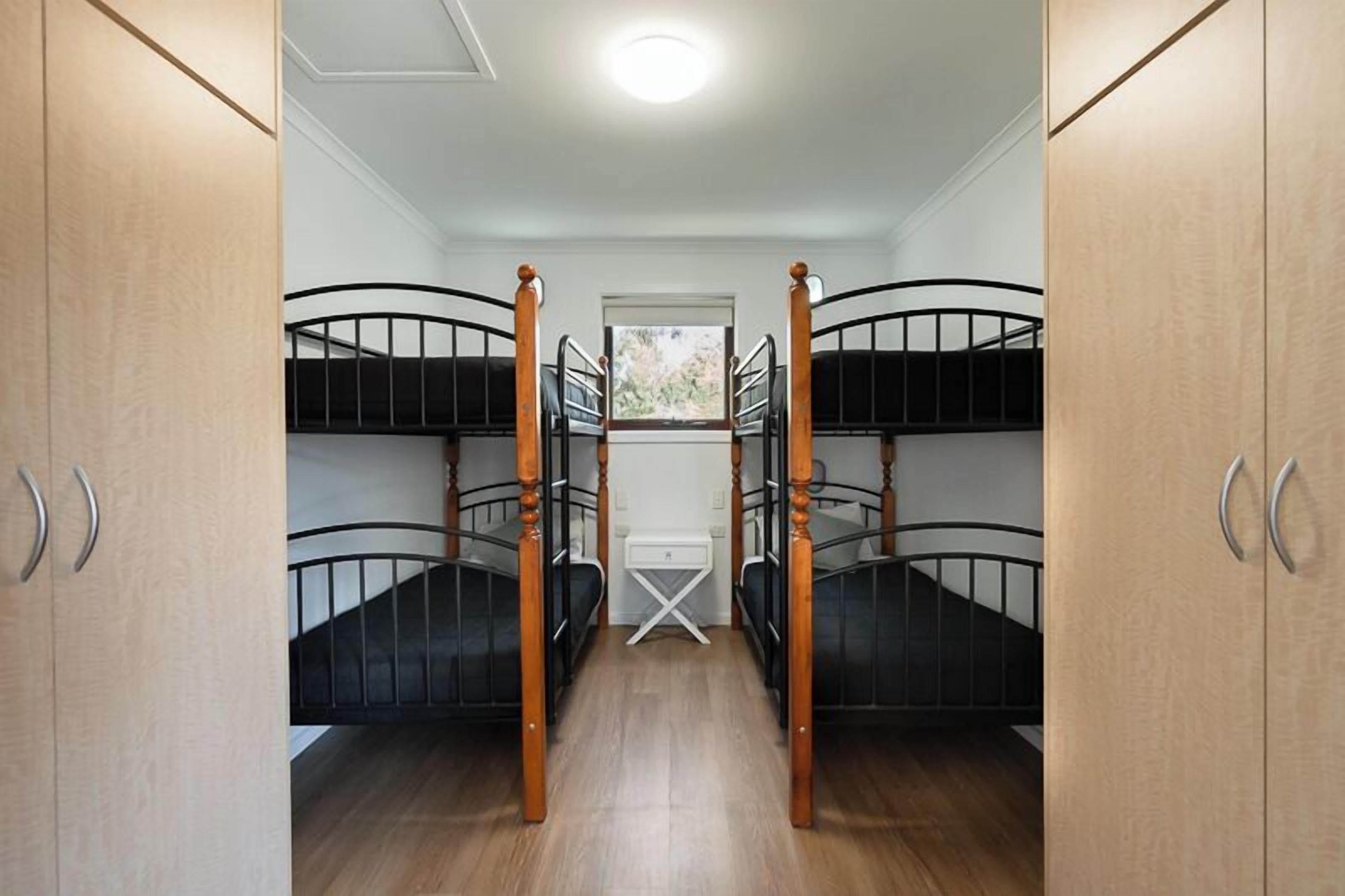 A room with bunk beds, wooden cabinets, and a window.