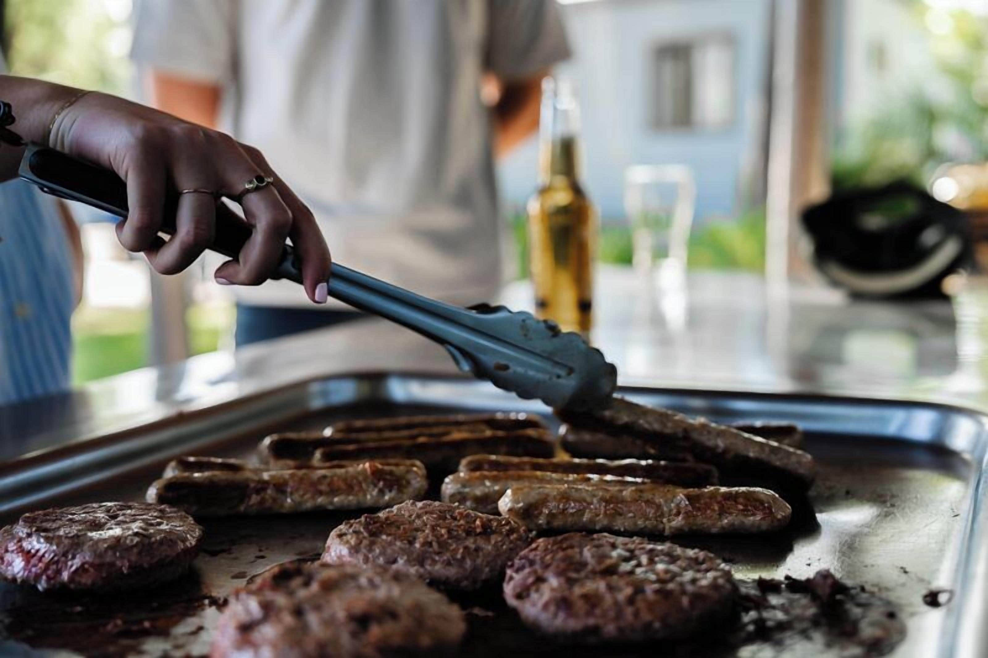 A person grilling hamburgers on a grill pan.