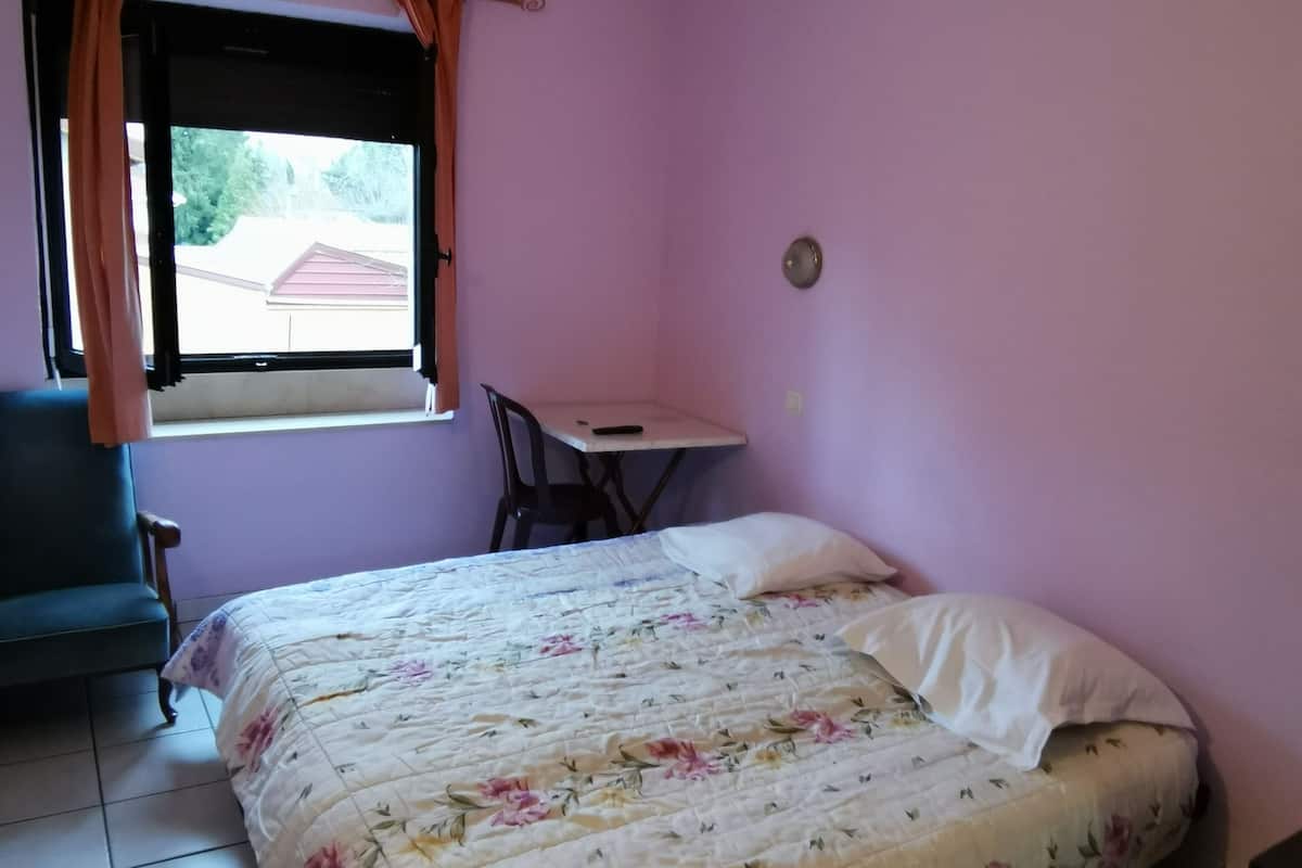 A bedroom with a bed, a desk, and a chair.