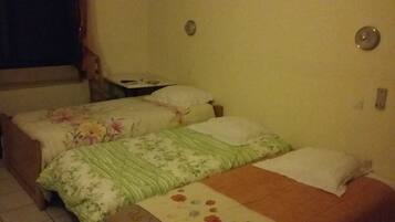 A bedroom with two beds, a nightstand, and a window with curtains.