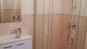 Une salle de bain avec une douche à parois de verre, un lavabo avec un miroir et des toilettes.