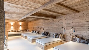 Uma sala de spa com paredes de madeira, várias camas e luminárias fixadas na parede.