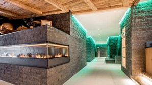 Um interior moderno com lareira de pedra, vigas de madeira e iluminação ambiente verde.