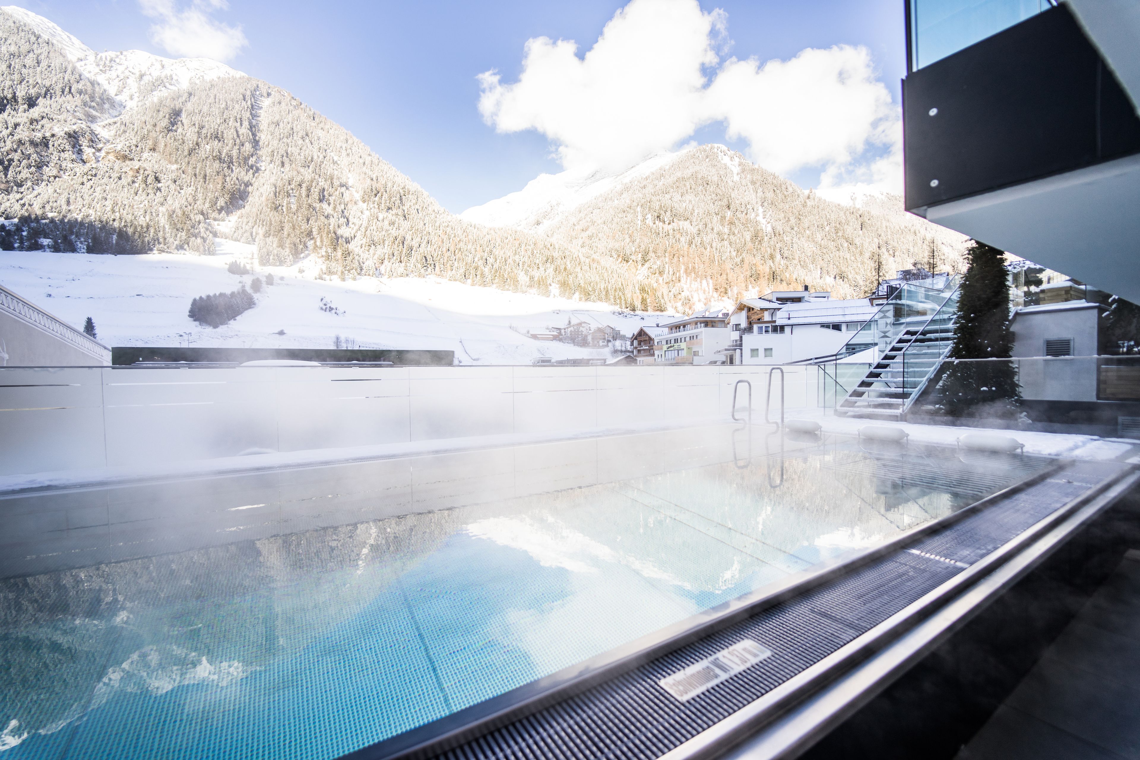 Un jacuzzi con vistas a montañas nevadas y un edificio al fondo.