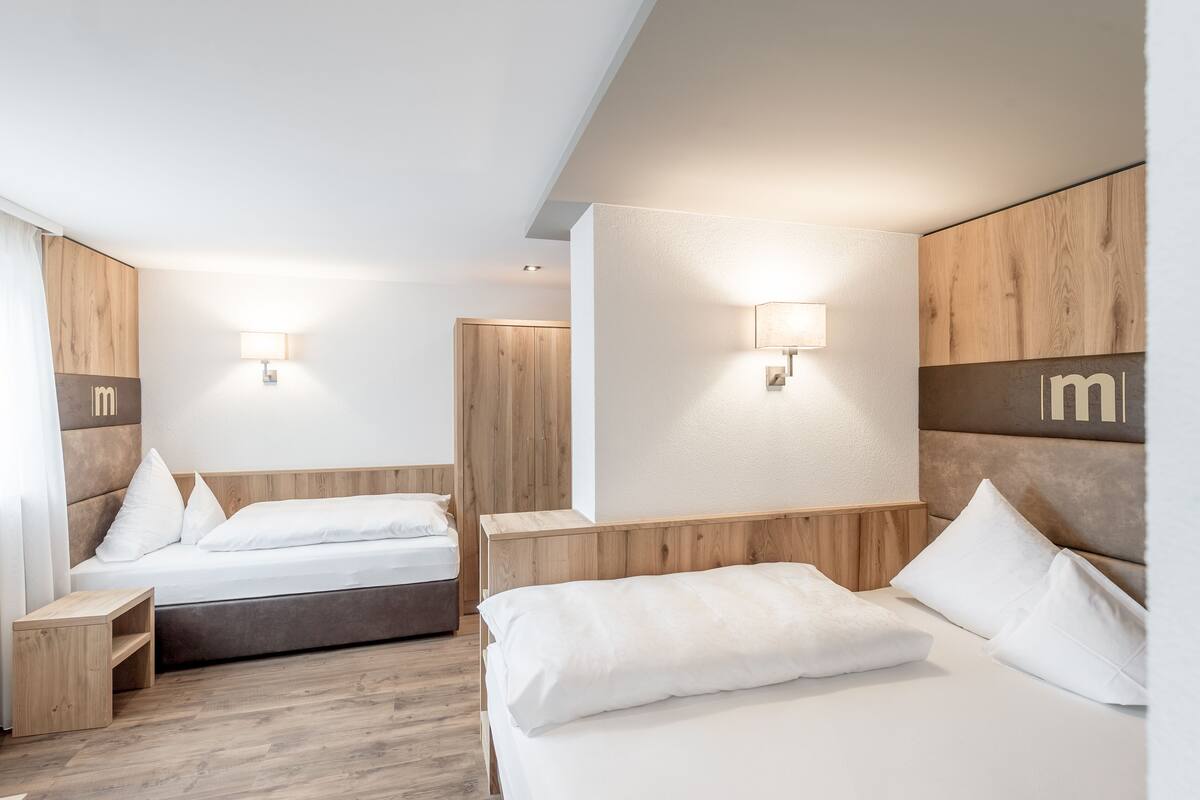 Une chambre d’hôtel avec deux lits, des têtes de lit en bois et des lampes fixées au mur.