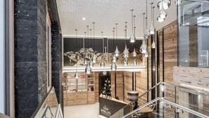 Interior de um spa moderno com um balcão de recepção de madeira, uma escadaria e iluminação pendente.