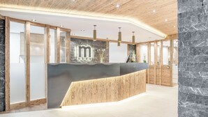 Uma área de recepção com balcão de madeira, paredes de mármore e design moderno no teto.