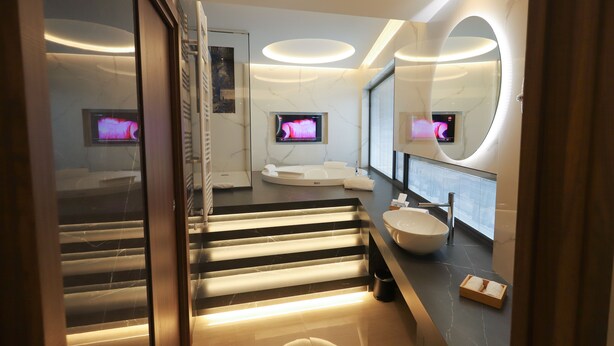 A modern bathroom with a marble floor, a large mirror, a sink, and a television mounted on the wall. - Bellavista (Giugliano in Campania)