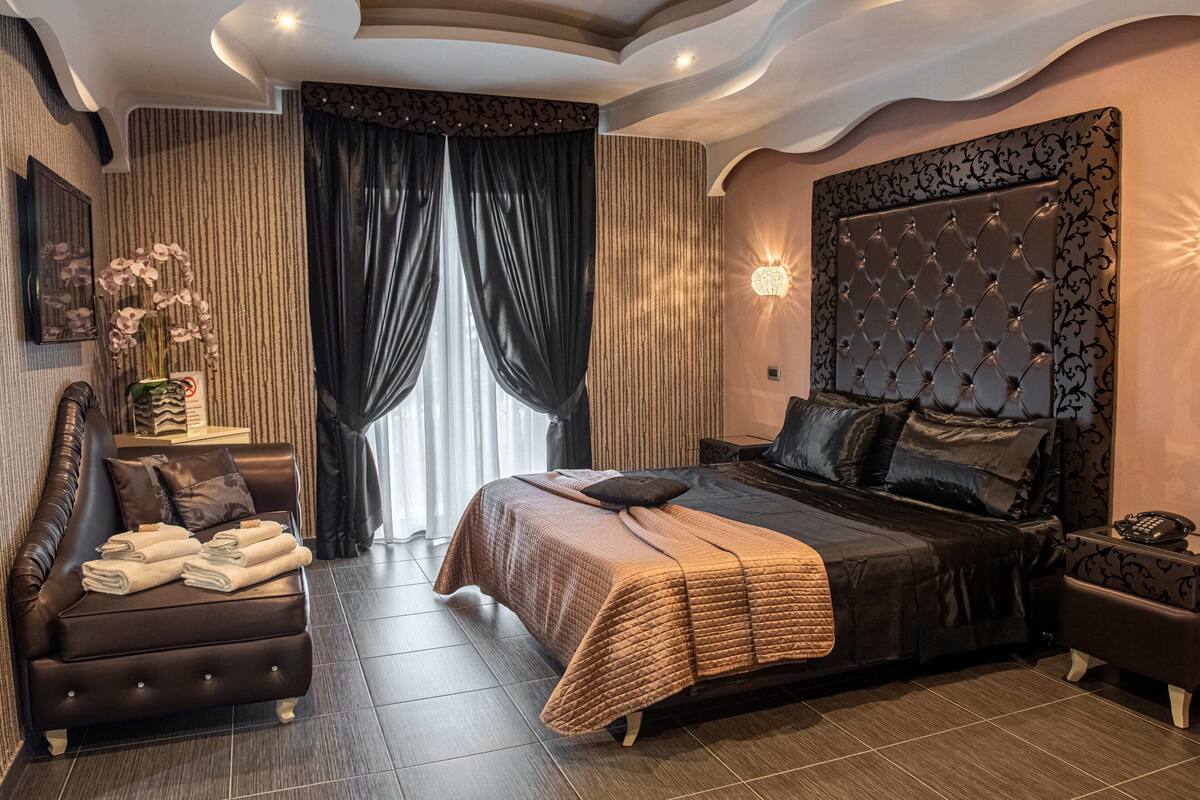 A modern bedroom with a large bed, a sofa, and a nightstand.