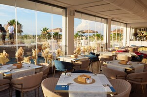 Un restaurante con terraza, ventanas amplias y vistas a la playa.