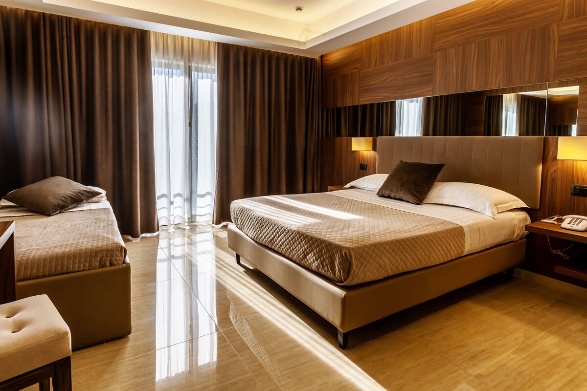 A modern hotel room with a large bed, a desk, and a chair.
