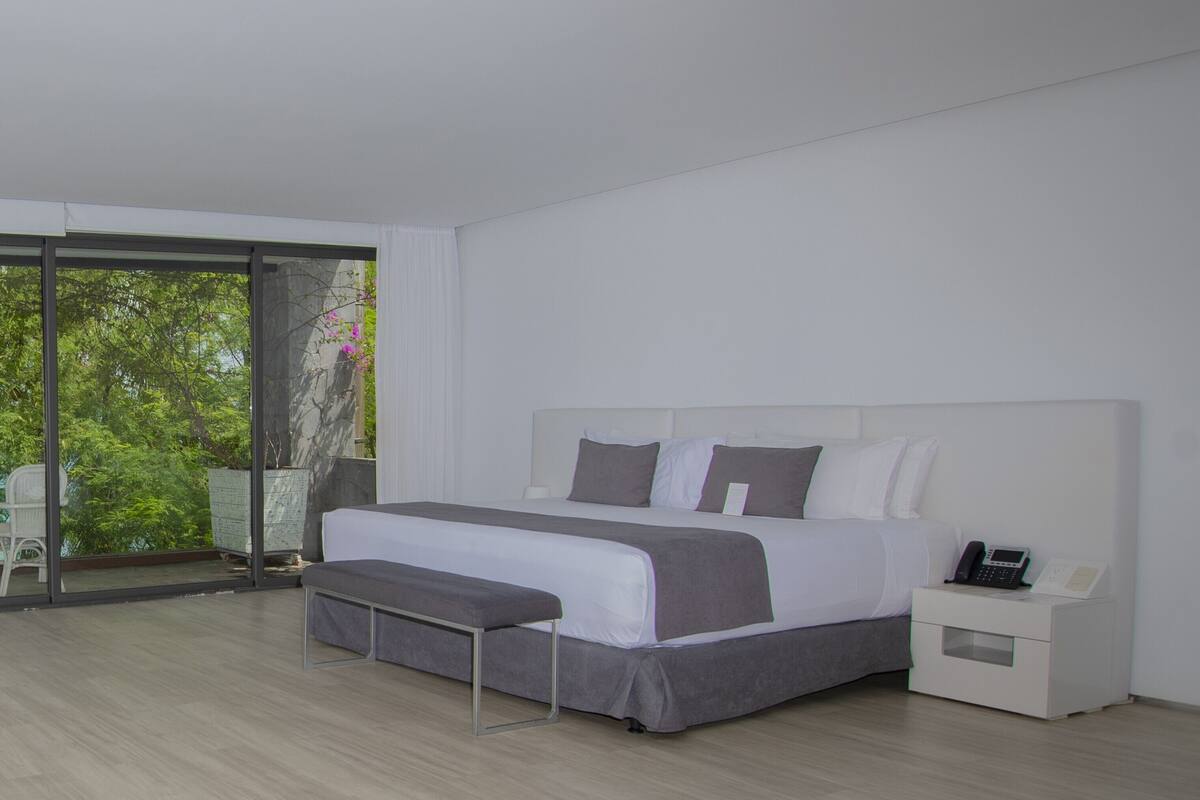 Une chambre à coucher moderne avec un grand lit, une table de chevet avec un téléphone et un banc.