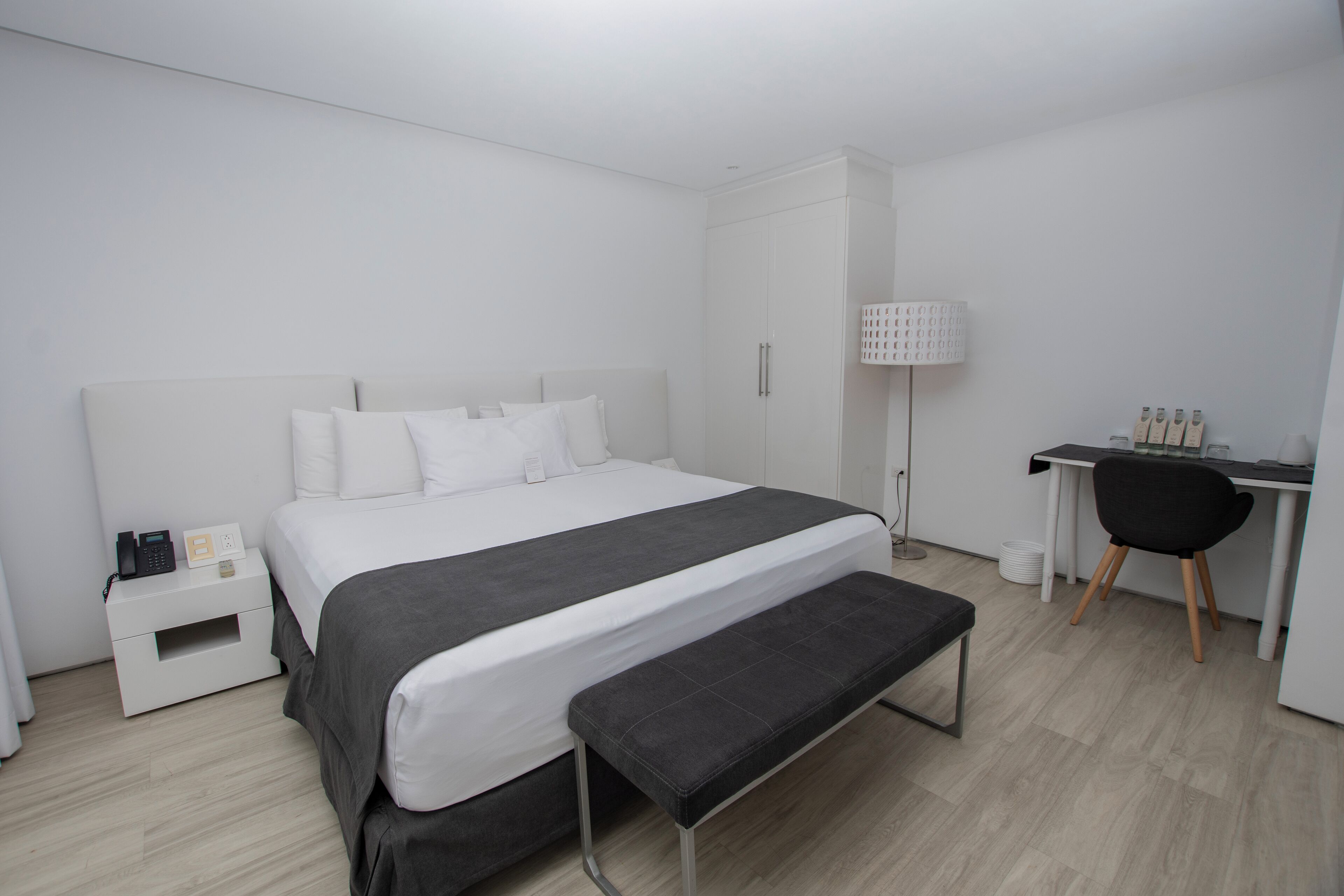 Una habitación de hotel moderna con una cama grande, un escritorio, una silla y un banco.