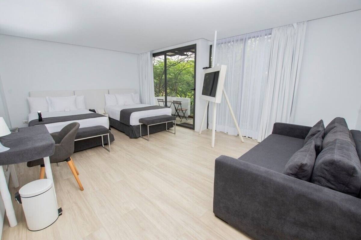 Une chambre d’hôtel moderne équipée de deux lits, d’un canapé, d’un bureau et d’une télévision.