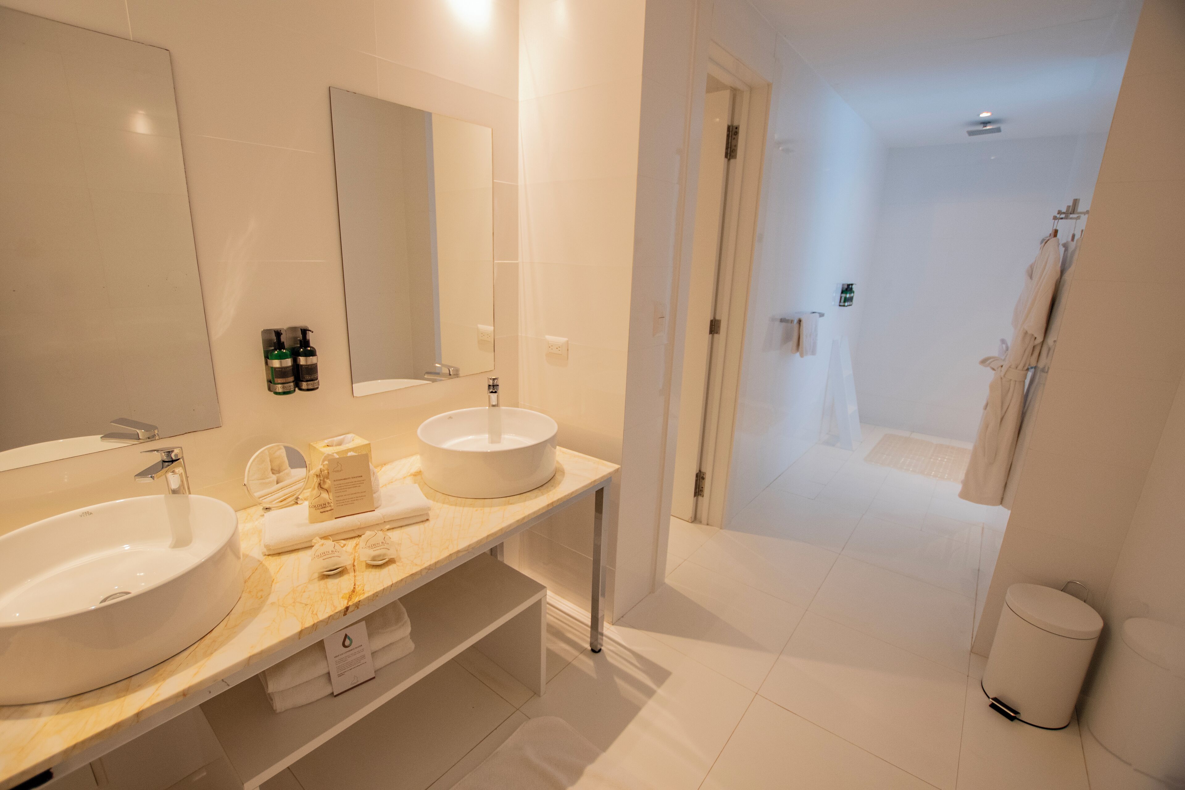 A modern bathroom with two sinks, a large mirror, and a shower area.
