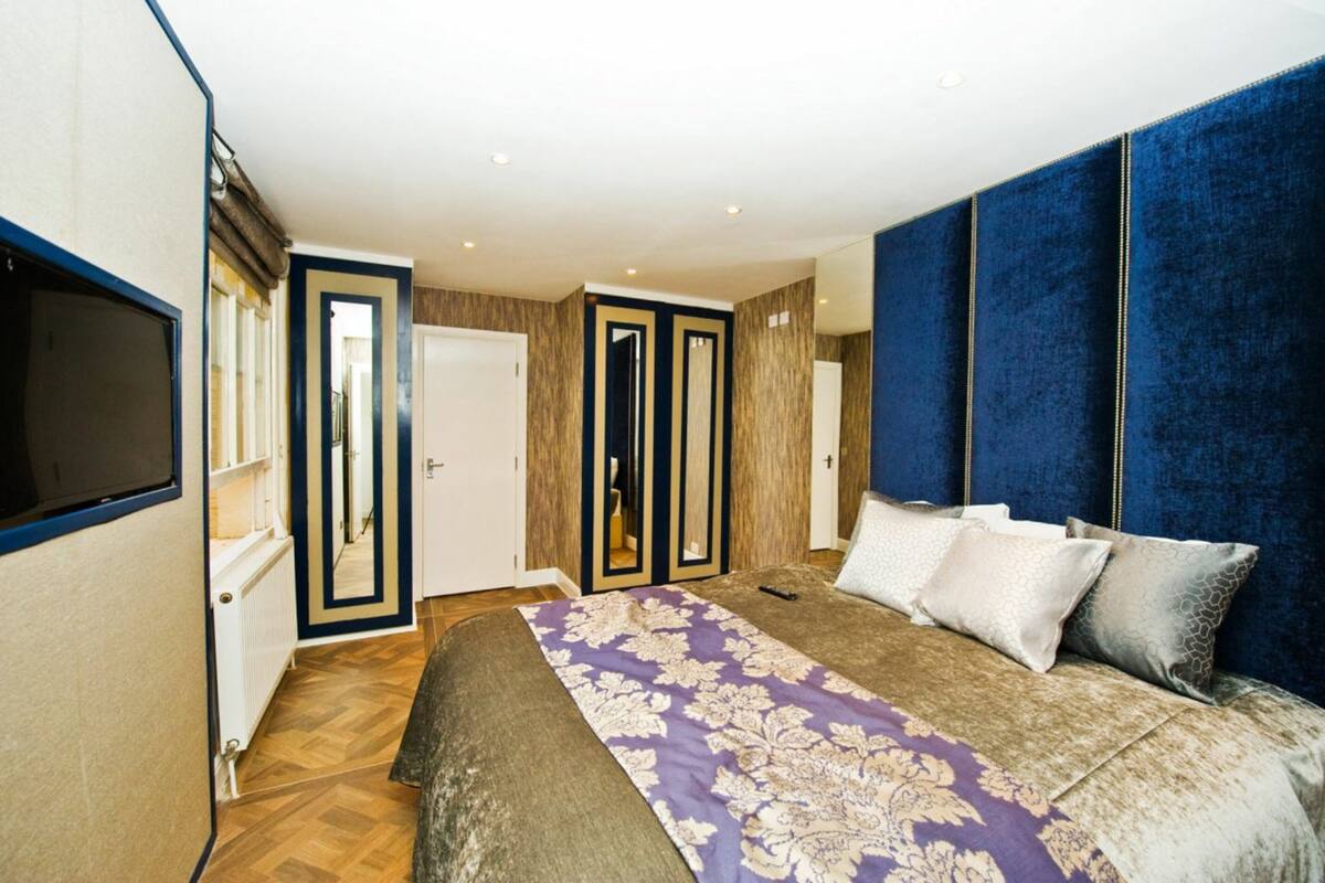 A bedroom with a large bed, a wardrobe, and a mirror.