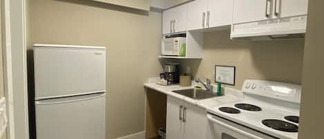 A compact kitchen with white appliances, a built-in microwave, and a stove.