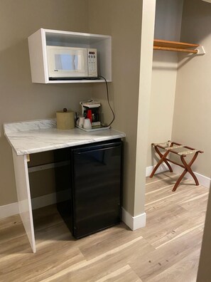 A compact kitchenette with a microwave, coffee maker, and a small refrigerator. - Imperial Motel (100 Mile House)