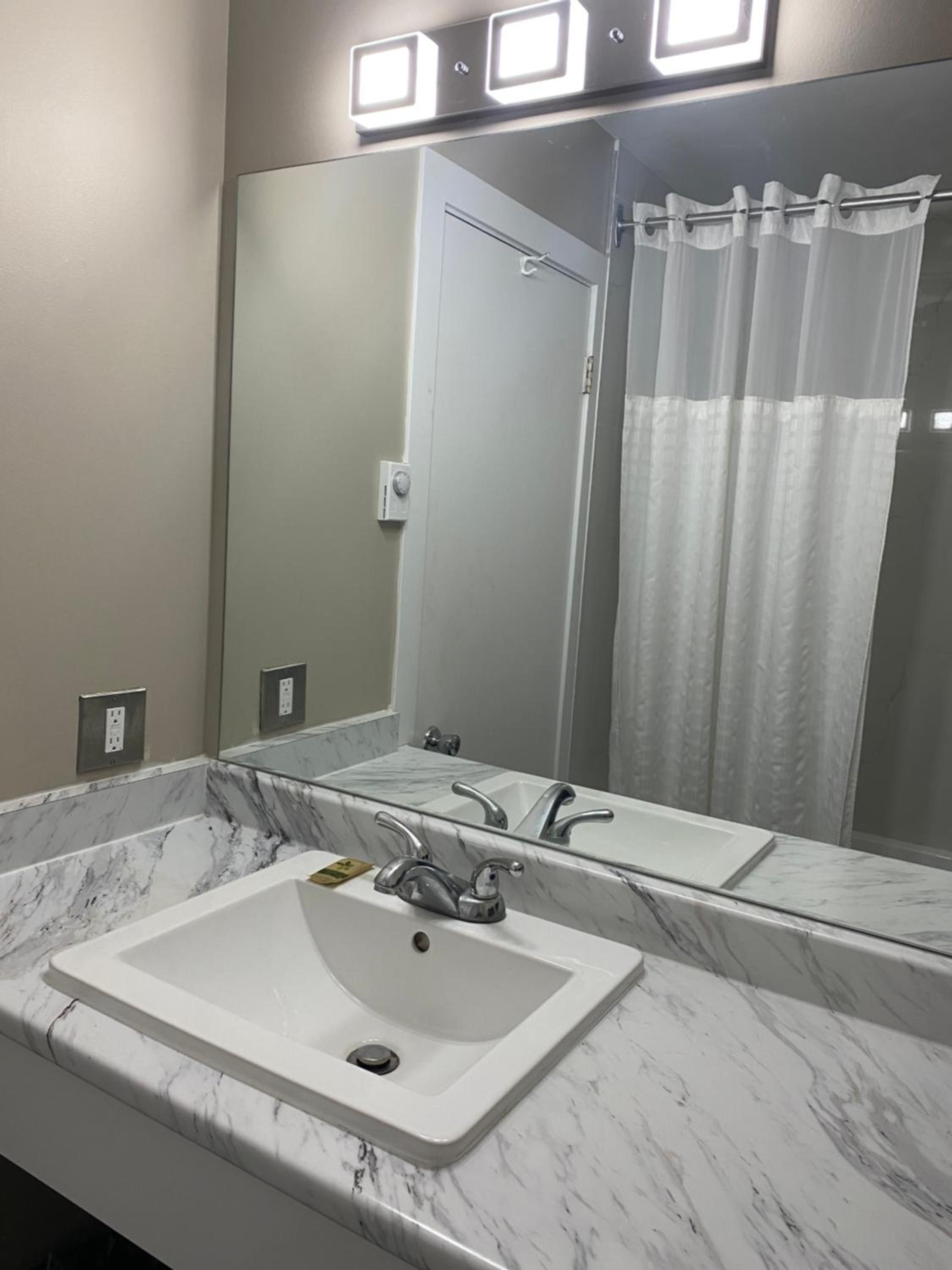 A bathroom with a marble sink, a mirror, and a shower curtain.