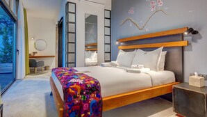 A modern bedroom with a large bed, a wooden headboard, a colorful blanket, a bedside table with a tissue box, and a wall-mounted air conditioner. - Villa Kore Cesme (Cesme)