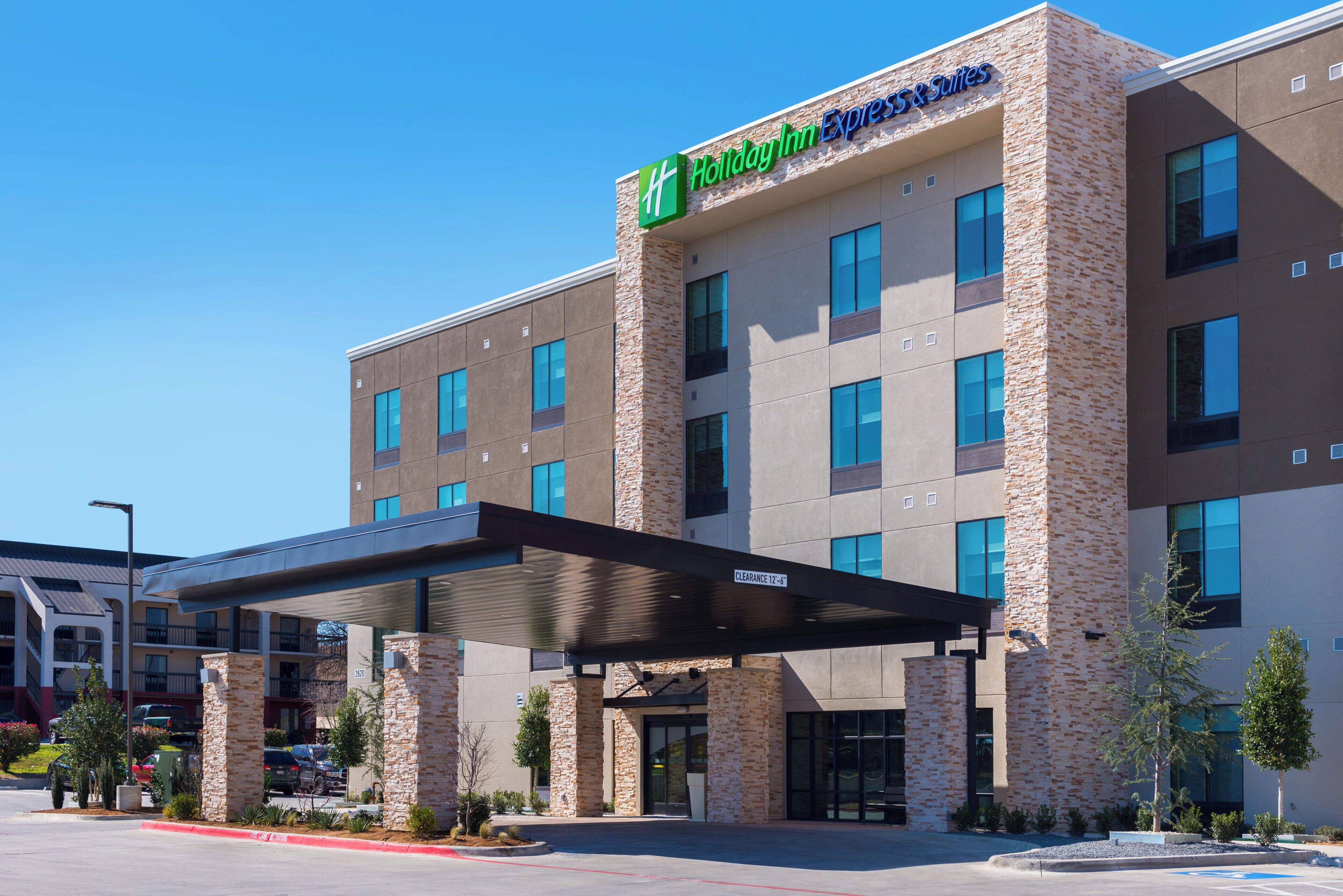 A Holiday Inn Express & Suites building with a stone facade, multiple windows, and a covered entrance.
