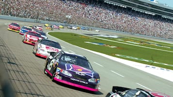 Una carrera con varios coches en la pista, rodeada por una gran multitud.