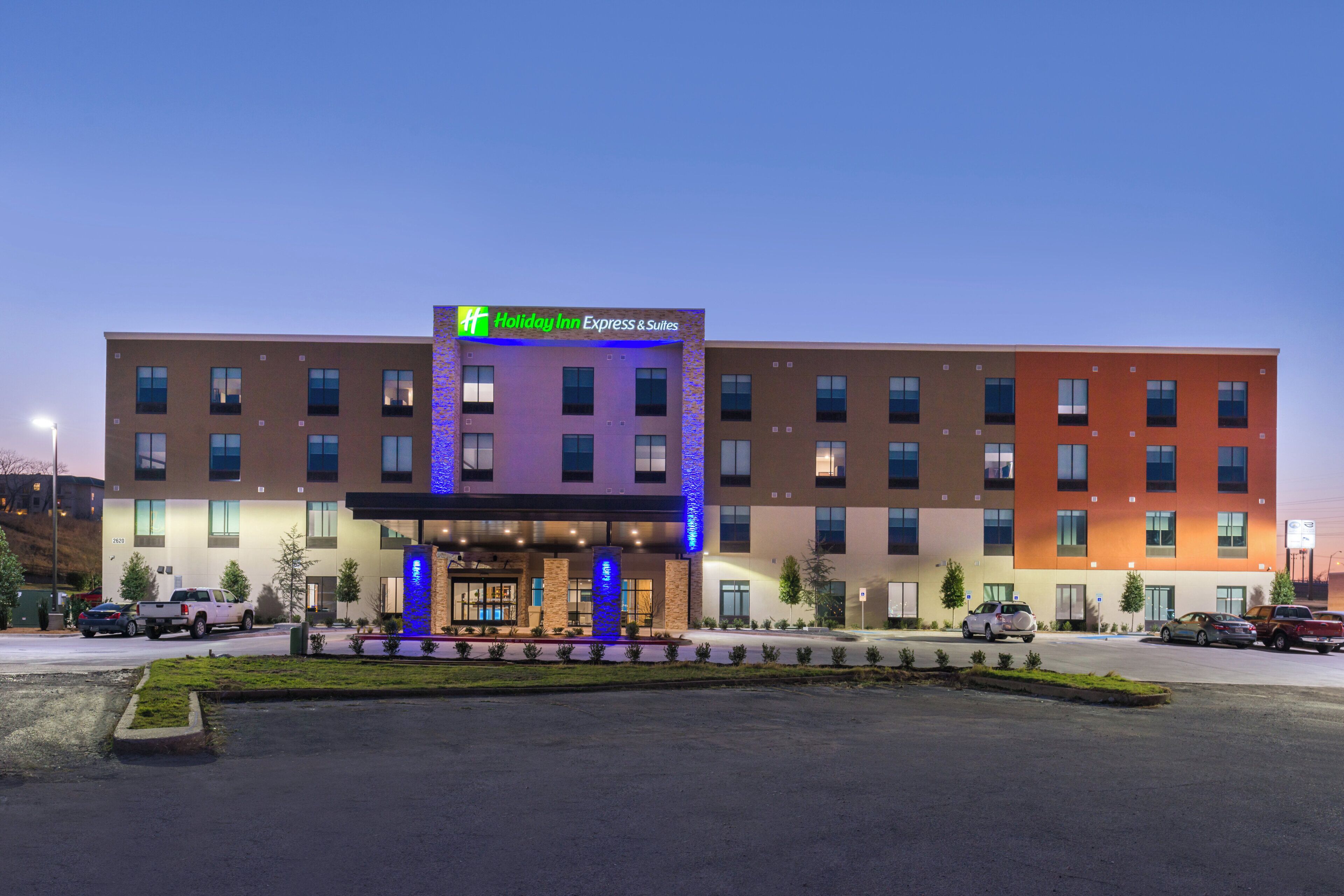 A Holiday Inn Express & Suites hotel with a modern facade, multiple entry points, and a parking lot.
