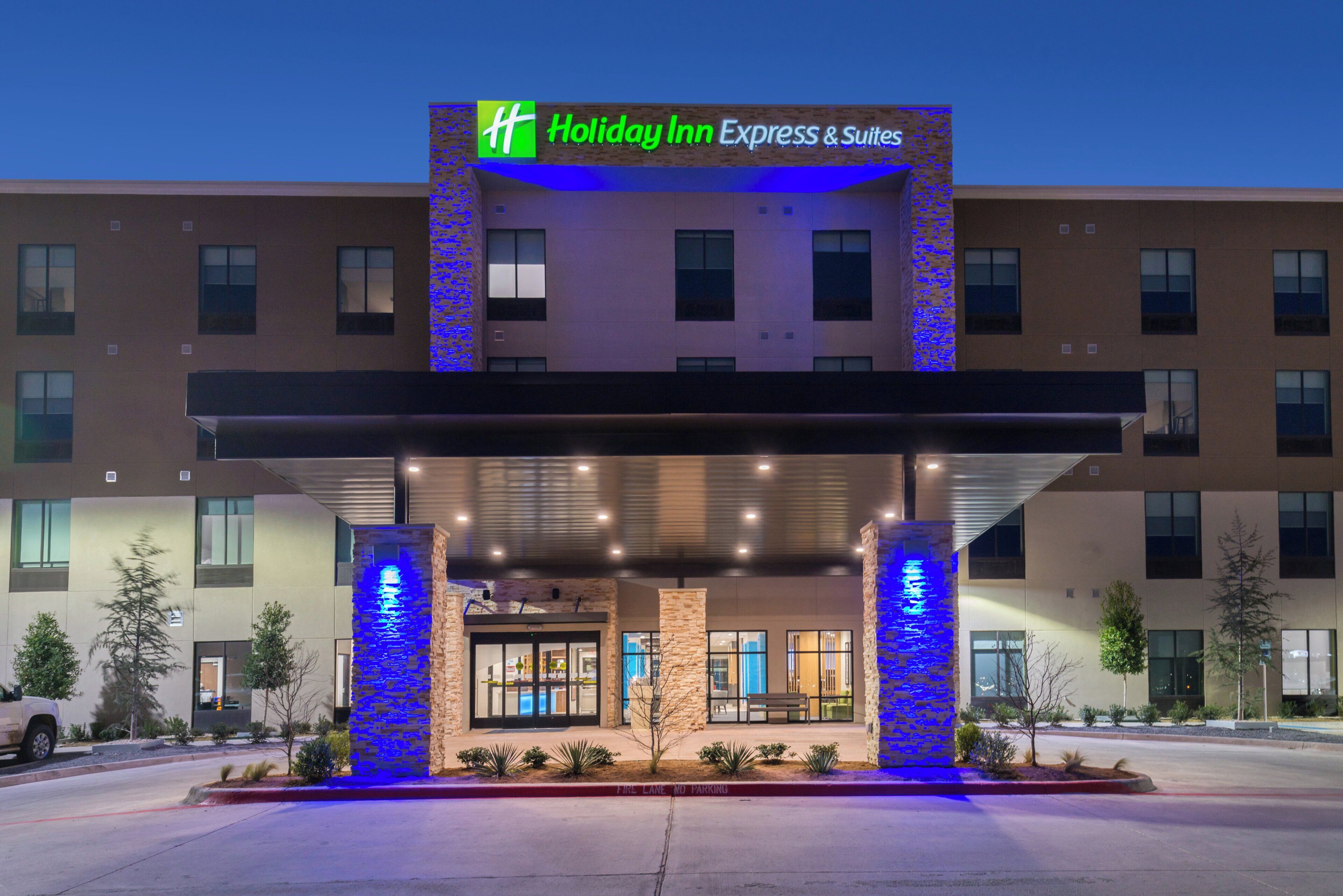 A Holiday Inn Express & Suites building with a covered entrance, stone pillars, and a sign above.