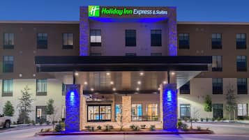 A Holiday Inn Express & Suites building with a covered entrance, stone pillars, and a sign above.