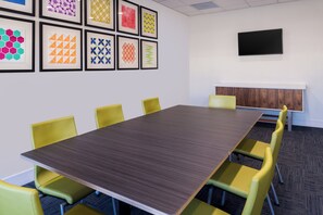 A conference room with a long table and yellow chairs, a flat-screen TV on the wall, and framed geometric patterns on the wall. - Holiday Inn Express & Suites Fort Worth West by IHG (Fort Worth)