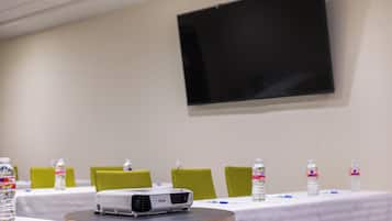 Ein Konferenzraum mit Projektor auf dem Tisch, Wasserflaschen und grünen Stühlen.