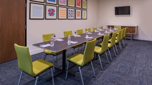 A conference room with a long table, yellow chairs, water bottles, and framed artwork on the wall. - Holiday Inn Express & Suites Fort Worth West by IHG (Fort Worth)