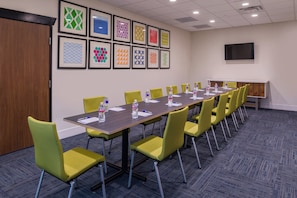 A conference room with a long table, yellow chairs, water bottles, and framed artwork on the wall. - Holiday Inn Express & Suites Fort Worth West by IHG (Fort Worth)