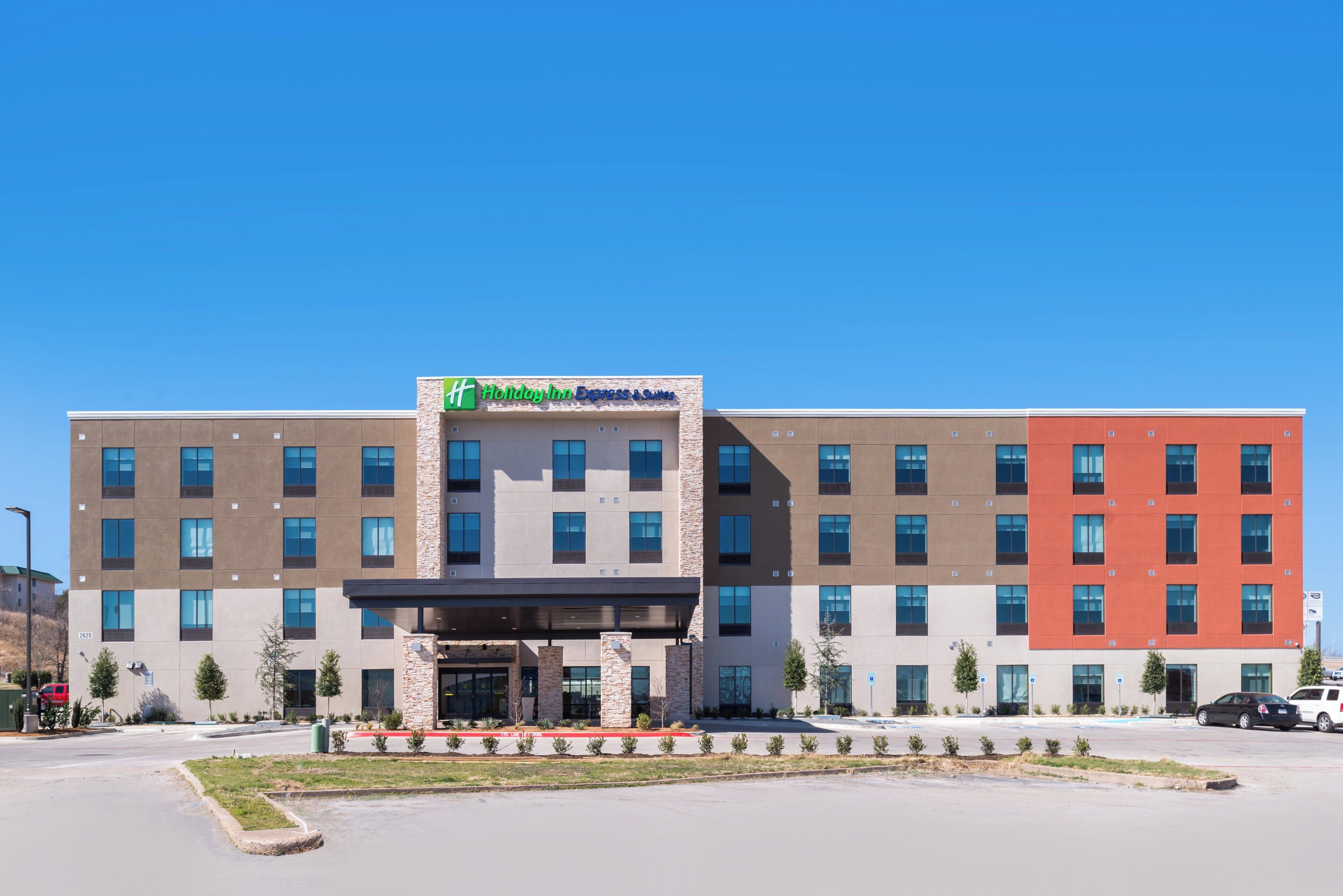 A multi-story Holiday Inn Express & Suites building with a flat roof, large windows, and a stone facade.