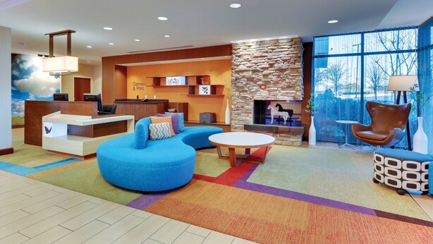 A modern lobby with a blue sofa, a round coffee table, and a fireplace. - Fairfield Inn & Suites Dunn I-95 (Dunn)