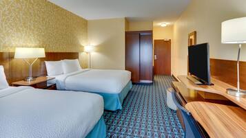 A hotel room with two beds, a TV, a desk, and a wardrobe.