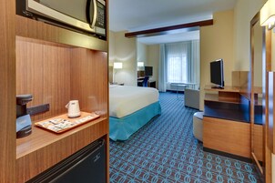 Habitación de hotel con cama, escritorio y televisor.