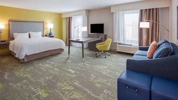 Una habitación de hotel con cama, escritorio, silla y sofá.