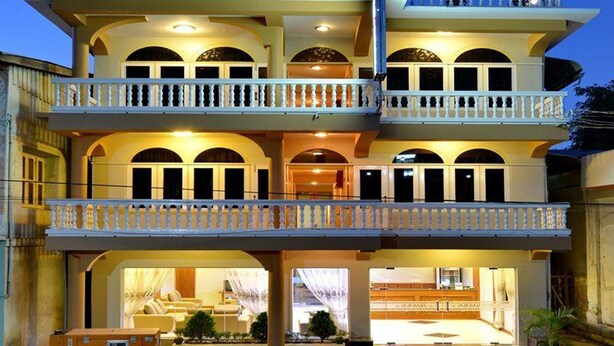 Un hotel de varios pisos con balcones, ventanas en arco y una entrada bien iluminada.