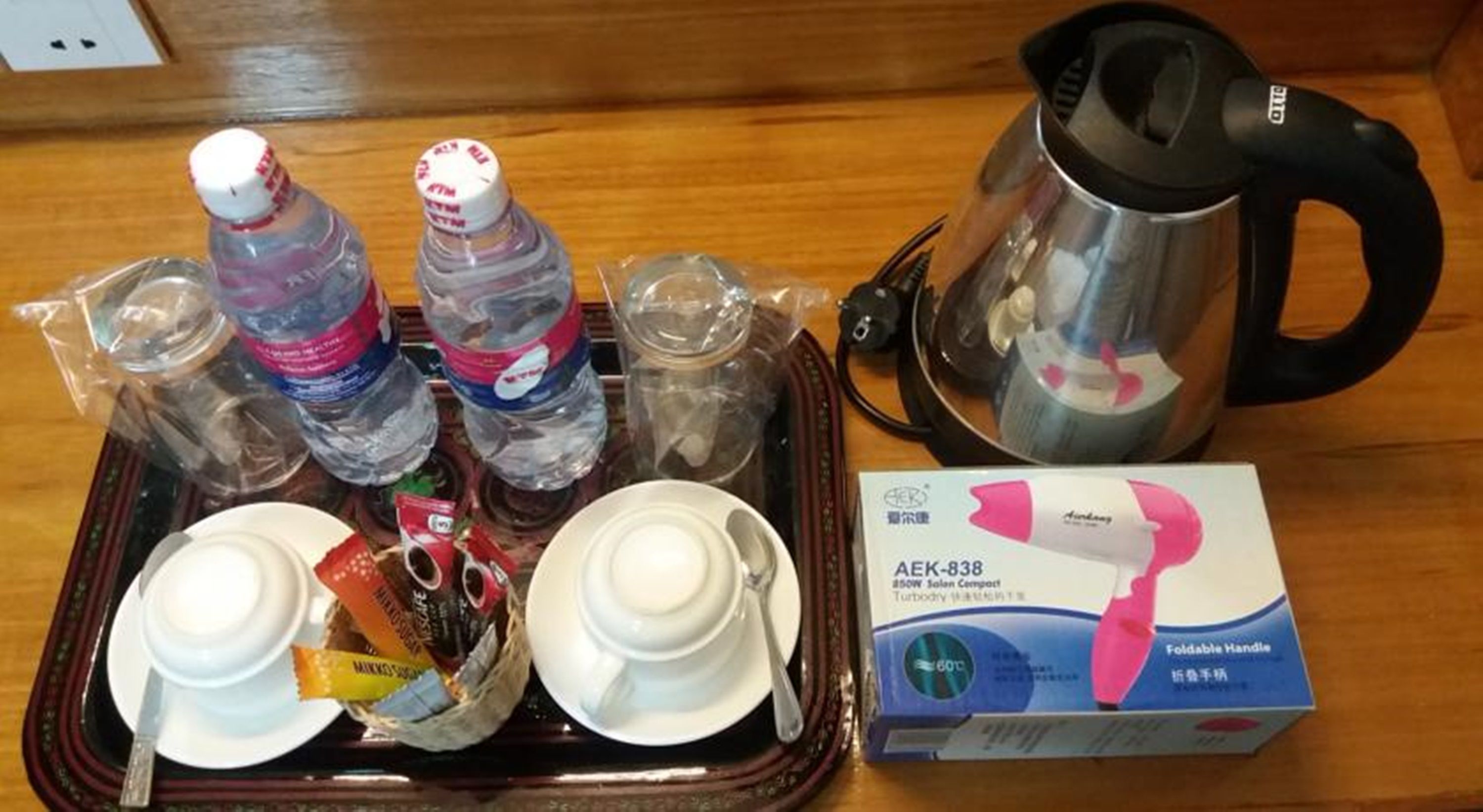 Una bandeja con botellas de agua, un hervidor y una caja de secador de pelo portátil.