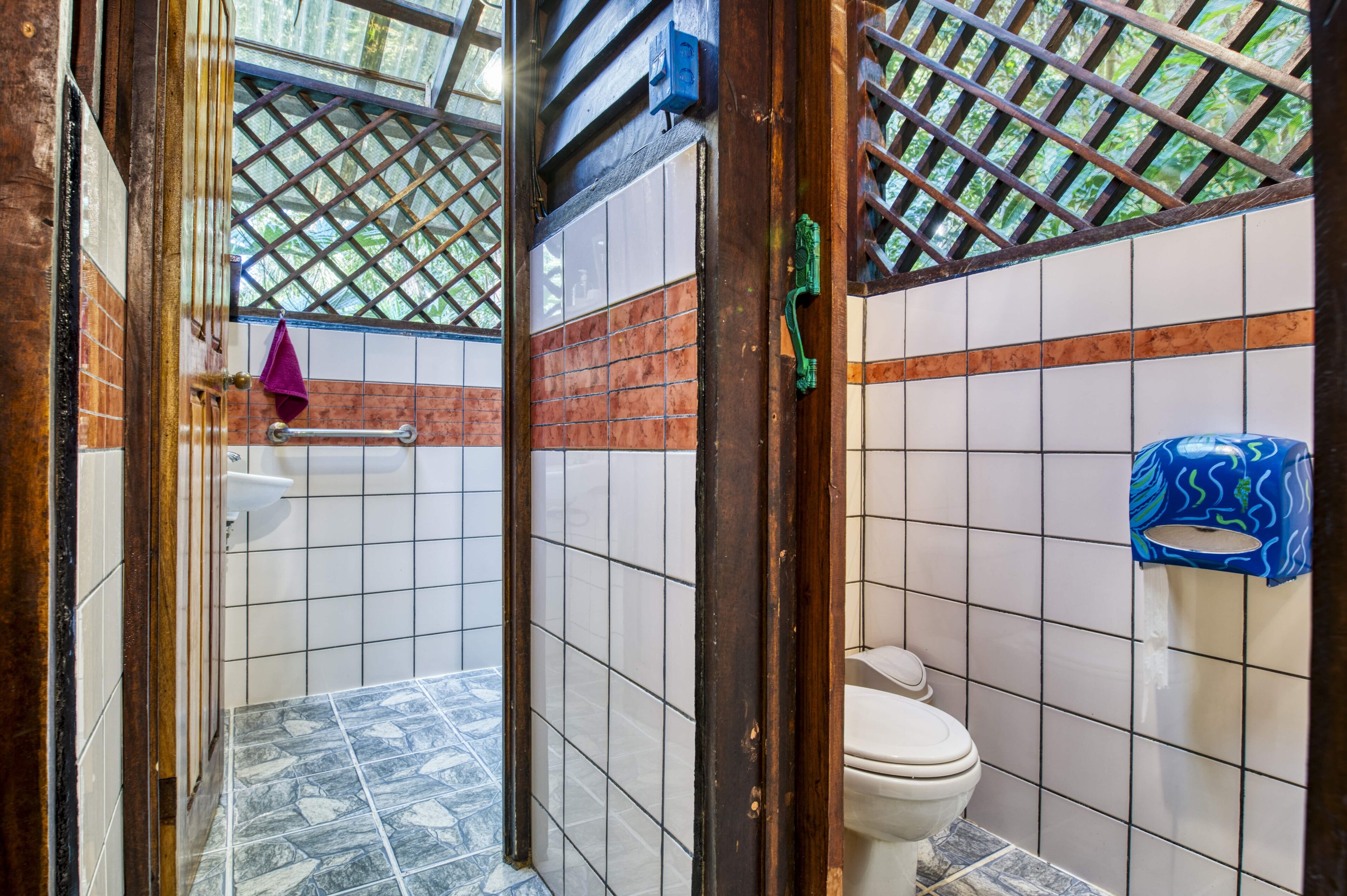 Casa de banho com chão em mosaico, sanita, lavatório e área de duche.